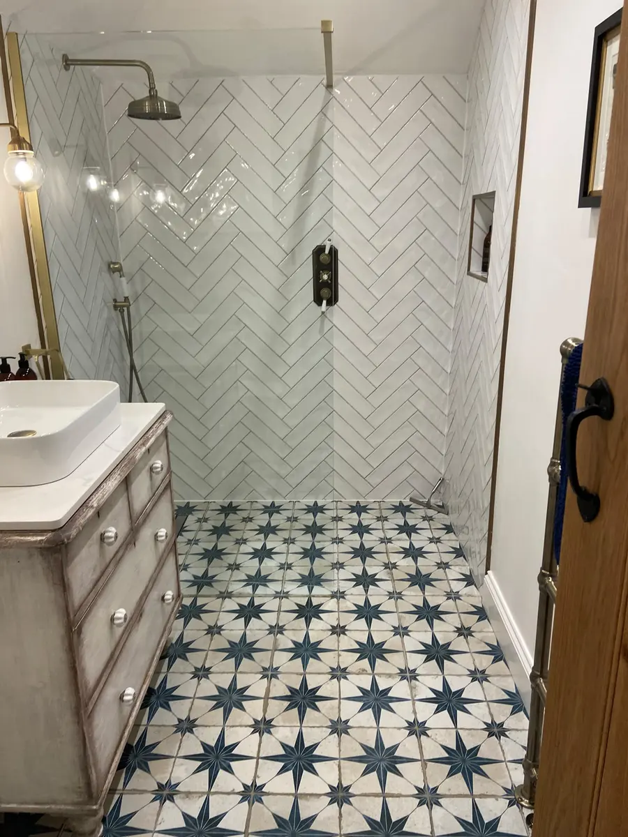 Walk-in shower with herringbone tiles and a patterned tile floor, clean and streak free
