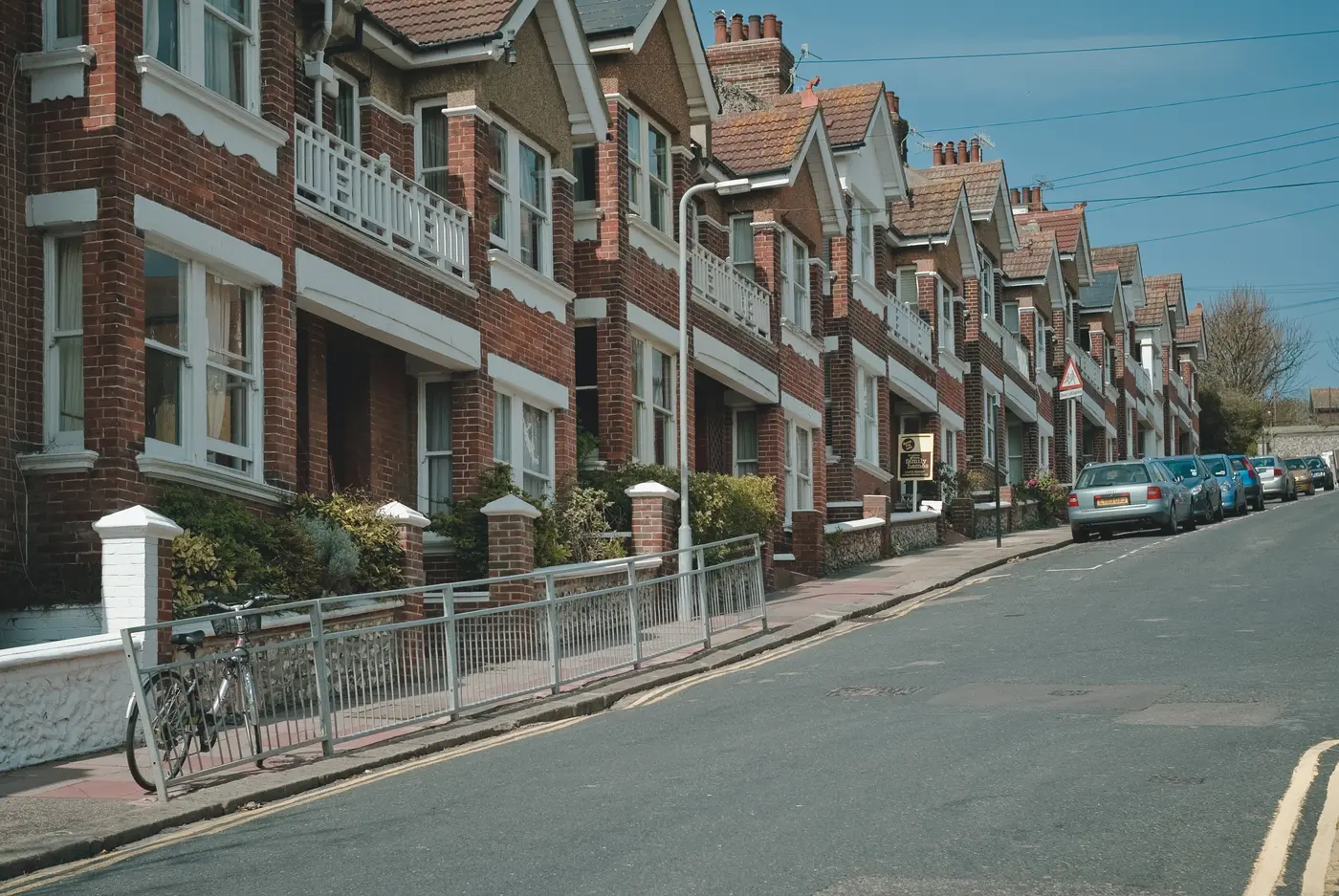 Long row of red brick Edwardian terraced houses on a quiet street